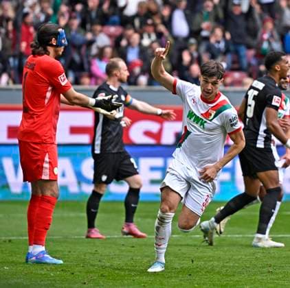 04.10.2025, Fussball 1. Bundesliga 2025 2026, 6.Spieltag, FC Augsburg - VfL Wolfsburg, in der WWK-Arena Augsburg. Mert Kömür (FC Augsburg) jubelt. Torwart Kamil Grabara (Wolfsburg) ist geschlagen.