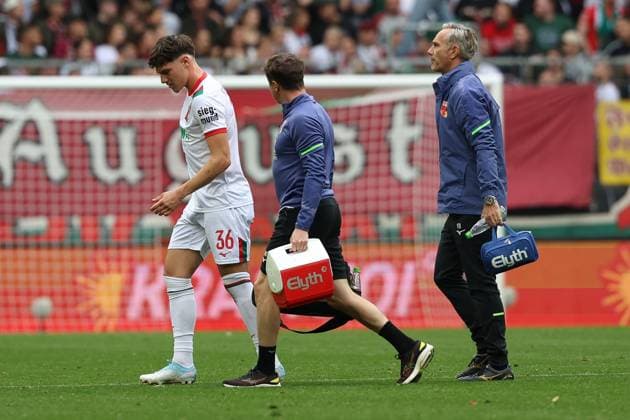 Mannschaftsarzt Dr. Karsten Bogner (FC Augsburg) unf Physiotherapeut, Nikolaus Guschl (FC Augsburg) schauen nach Mert Koemuer 36 (FC Augsburg), FC Augsburg vs. VfL Wolfsburg, Fussball, 1. Bundesliga, 6. Spieltag, 04.10.2025 DFB regulations prohibit any use of photographs as image sequences and or quasi-video Augsburg Bayern Deutschland