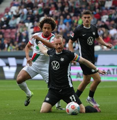 04.10.2025, 1. Bundesliga , FC Augsburg vs VfL Wolfsburg, WWK Arena Augsburg , Fussball, im Bild: Han-Noah Massengo (FC Augsburg) fault Maximilian Arnold (VfL Wolfsburg), Joakim Maehle (VfL Wolfsburg) schaut zu