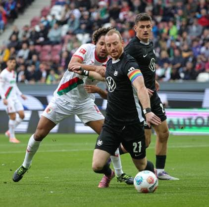 04.10.2025, 1. Bundesliga , FC Augsburg vs VfL Wolfsburg, WWK Arena Augsburg , Fussball, im Bild: Han-Noah Massengo (FC Augsburg) fault Maximilian Arnold (VfL Wolfsburg), Joakim Maehle (VfL Wolfsburg) schaut zu