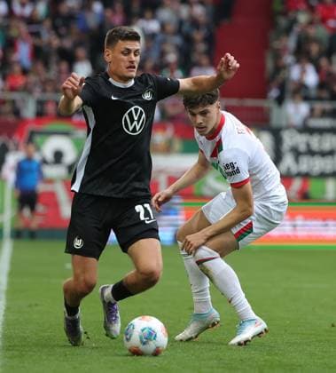 04.10.2025, 1. Bundesliga , FC Augsburg vs VfL Wolfsburg, WWK Arena Augsburg , Fussball, im Bild: Joakim Maehle (VfL Wolfsburg) vs Mert Koemuer (FC Augsburg)