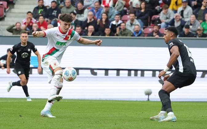 04.10.2025, 1. Bundesliga , FC Augsburg vs VfL Wolfsburg, WWK Arena Augsburg , Fussball, im Bild: Mert Koemuer (FC Augsburg) vs Moritz Jens (VfL Wolfsburg)