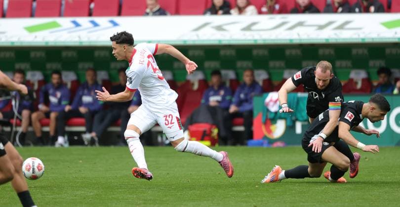 04.10.2025, 1. Bundesliga , FC Augsburg vs VfL Wolfsburg, WWK Arena Augsburg , Fussball, im Bild: Fabian Rieder (FC Augsburg) laesst Maximilian Arnold (VfL Wolfsburg) und Moritz Jens (VfL Wolfsburg) liegen