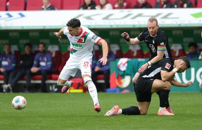 04.10.2025, 1. Bundesliga , FC Augsburg vs VfL Wolfsburg, WWK Arena Augsburg , Fussball, im Bild: Fabian Rieder (FC Augsburg) laesst Maximilian Arnold (VfL Wolfsburg) und Moritz Jens (VfL Wolfsburg) liegen