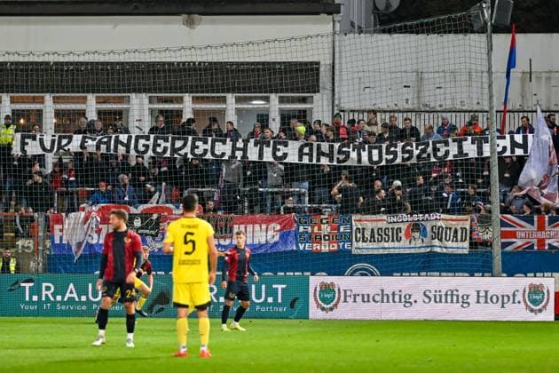 Unterhachinger Fans skandieren gegen die Anstoßzeiten und halten ein entsprechendes Banner hoch FÜR FANGERECHTE ANSTOSSZEITEN , Fans, Publikum, Zuschauer, Stimmung, Atmosphäre, Stadion, 17.10.2025, Unterhaching (Deutschland), Fussball, Regionalliga Bayern, SpVgg Unterhaching - SpVgg Bayreuth