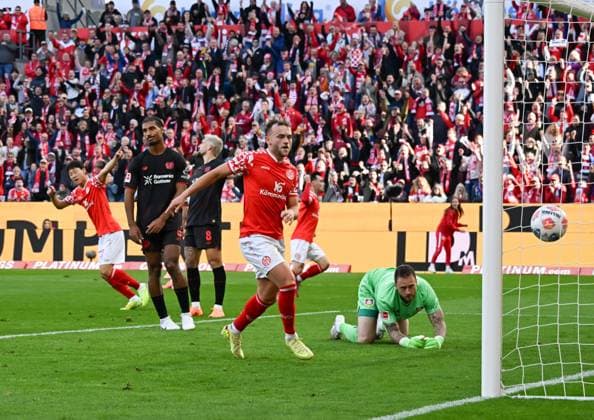 18.10.2025, xsltx, Fussball 1.Bundesliga, FSV Mainz 05 - Bayer 04 Leverkusen v.l. Jae-Sung Lee (1. FSV Mainz 05) trifft zum 1:2-Anschlusstor für Mainz, Mark Flekken (Bayer 04 Leverkusen) hat das Nachsehen (DFL DFB REGULATIONS PROHIBIT ANY USE OF PHOTOGRAPHS as IMAGE SEQUENCES and or QUASI-VIDEO)