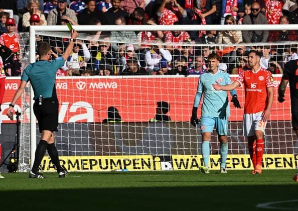 18.10.2025, xsltx, Fussball 1.Bundesliga, FSV Mainz 05 - Bayer 04 Leverkusen v.l. Dr. Florian Exner (Schiedsrichter) zeigt Dominik Kohr (1. FSV Mainz 05 re.) die gelbe Karte (DFL DFB REGULATIONS PROHIBIT ANY USE OF PHOTOGRAPHS as IMAGE SEQUENCES and or QUASI-VIDEO)