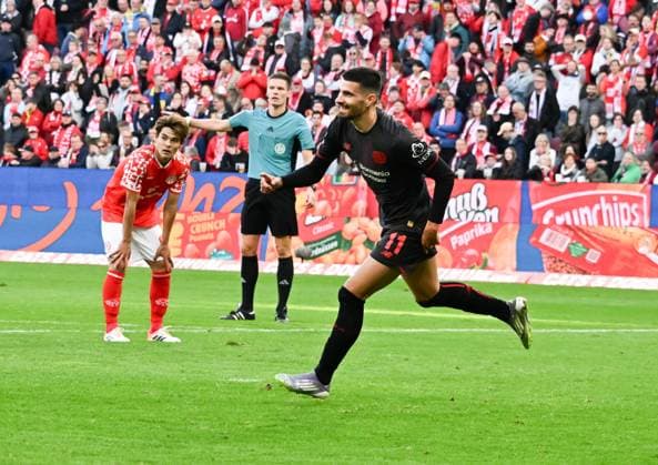 18.10.2025, xsltx, Fussball 1.Bundesliga, FSV Mainz 05 - Bayer 04 Leverkusen v.l. Martin Terrier (Bayer 04 Leverkusen) jubelt über sein Tor zum 4:2, im Hintergrund ein enttäuschter Kaishu Sano (1. FSV Mainz 05), re. Dr. Florian Exner (Schiedsrichter) (DFL DFB REGULATIONS PROHIBIT ANY USE OF PHOTOGRAPHS as IMAGE SEQUENCES and or QUASI-VIDEO)