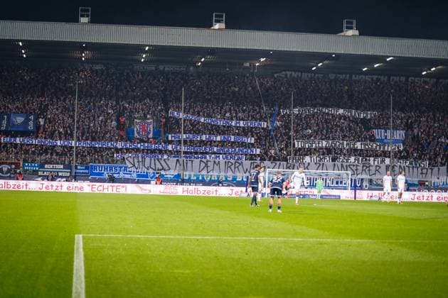 Deutschland: Fußball 2. Bundesliga 2025 26, 9. Spieltag VfL Bochum vs Hertha BSC Berlin Vonovia Ruhrstadion (Bochum): Große Fanproteste auf der Südtribüne mit Transparenten gegen Vereinsführung und sportliche Entwicklung. Botschaften zu Transparenz, Fankultur und Identität. Fußballfans, Support, Protest, Emotion, Ruhrpott, VfL Bochum, Hertha BSC, 2. Bundesliga.