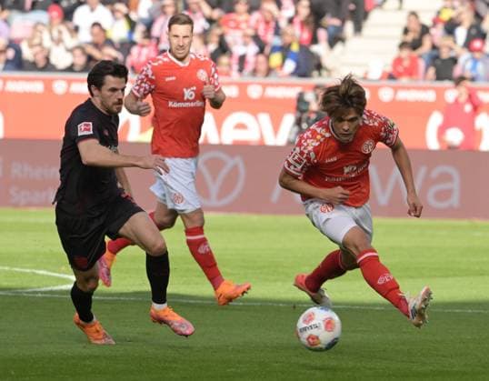 Kaishu Sano (re). gegen. Jonas Hofmann fotografiert beim Fußball Bundesliga Spiel Mainz 05 gegen Bayer 04. Leverkusen am 18.10.2025 in Mainz (DFL DFB REGULATIONS PROHIBIT ANY USE OF PHOTOGRAPHS as IMAGE SEQUENCES and or QUASI-VIDEO)