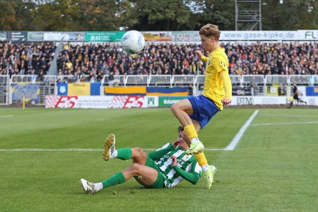 Fußball Regionalliga Nordost: 1. FC Lok Leipzig - BSG Chemie Leipzig; 19.10.2025 Christoph Maier (21, Lok Leipzig) überspringt Lorenz Hollenbach (3, Chemie Leipzig). Fußball, Regionalliga Nordost, Saison 2025 2026, 12. Spieltag: 1. FC Lok Leipzig vs. BSG Chemie Leipzig am 19.10.2025 im Bruno-Plache-Stadion, Leipzig. Copyright: xBEAUTIFULxSPORTS JanxKaeferx