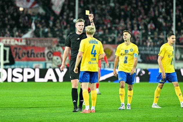 Fußball I Herren I Saison 2025-2026 I Regionalliga I 13. Spieltag I Hallescher FC - 1. FC Lokomotive Leipzig I 24.10.2025 Schiedsrichter Marvin Tennes zeigt Jan-Philipp Stein (4, 1. FC Lokomotive Leipzig) die gelbe Karte nach dem Foul an Halles Elezi Halle (Saale) Leuna-Chemie-Stadion Sachsen-Anhalt Deutschland Copyright: xLobeca InesxHähnelx