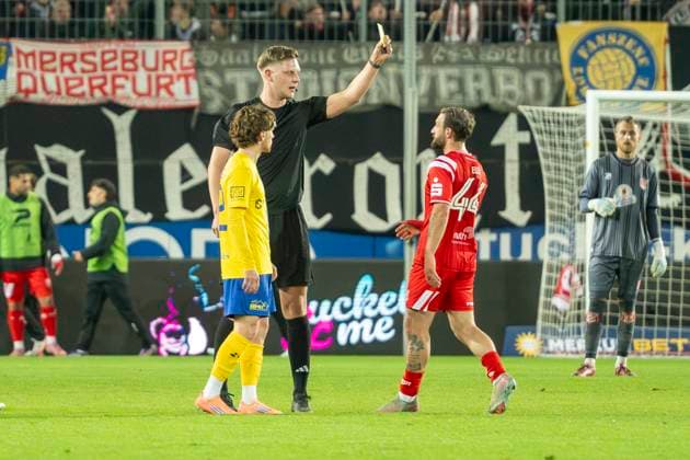 Regionalliga Nordost -Saison 25 26 Hallescher FC vs. 1.FC Lok Leipzig Halle, Deutschland 24.Oktober 2025: Im Bild:v.li.Dorian Cevis (Leipzig),Schiedsrichter Marvin Tennes und Fatlum Elezi (Halle) Gelb, gelbe Karte, Halle Saale Leuna Chemie Stadion Sachsen-Anhalt Deutschland