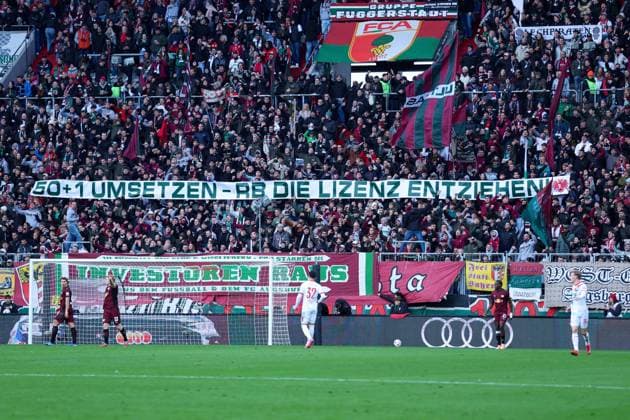 Fußball 1. Bundesliga 8. Spieltag FC Augsburg - RB Leipzig am 25.10.2025 in der WWK Arena in Augsburg Spruchband Banner im FC Augsburg Fanblock mit der Aufschrift: 50 + 1 UMSETZTEN - RB DIE LIZENZ ENTZIEHEN! DFL regulations prohibit any use of photographs as image sequences and or quasi-video.