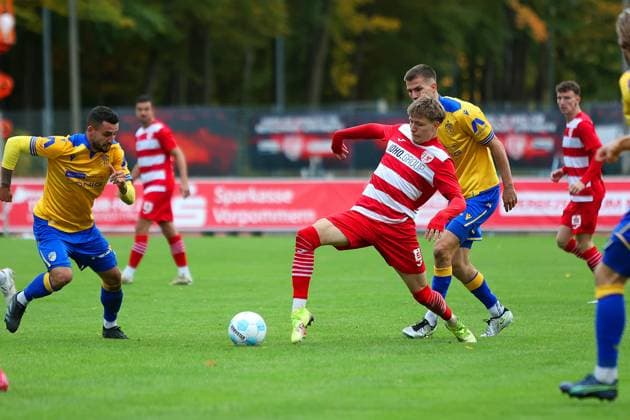 Bild: v.li.: Tristan Wagner 26(Greifswalder FC) vs. Moritz Fritz 23(FC Carl Zeiss Jena) --- Regionalliga Nordost Greifswalder FC (rot) gegen FC Carl Zeiss Jena (gelb) 25.10.2025 in Greifswald