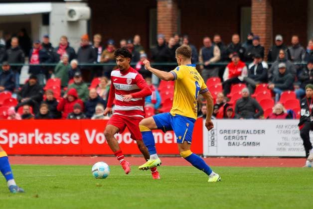 Bild: v.li.: Osman Atilgan 99(Greifswalder FC) vs. Maurice Hehne 6(FC Carl Zeiss Jena) --- Regionalliga Nordost Greifswalder FC (rot) gegen FC Carl Zeiss Jena (gelb) 25.10.2025 in Greifswald