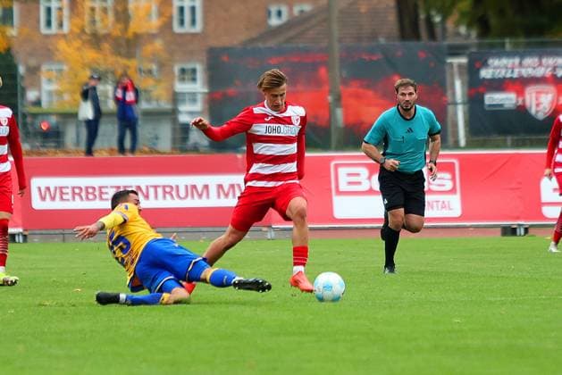 Bild: v.li.: Justin Schau 25(FC Carl Zeiss Jena) vs. Theo Harz 33(Greifswalder FC) --- Regionalliga Nordost Greifswalder FC (rot) gegen FC Carl Zeiss Jena (gelb) 25.10.2025 in Greifswald