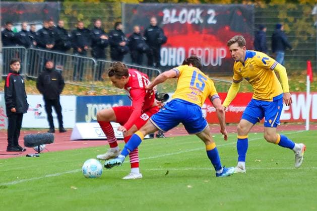 Bild: v.li.: Joe-Joe Richardson 10(Greifswalder FC) vs. Marcel Hoppe 15(FC Carl Zeiss Jena) --- Regionalliga Nordost Greifswalder FC (rot) gegen FC Carl Zeiss Jena (gelb) 25.10.2025 in Greifswald