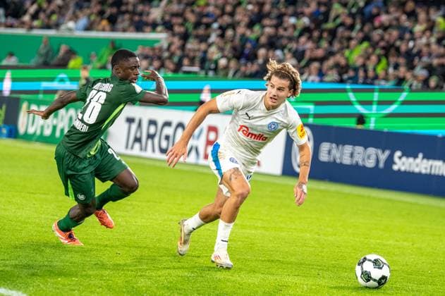 Deutschland, Fussball, DFB-Pokal, 2. Runde, 2025 2026, VfL Wolfsburg - Holstein Kiel am 28.10. in Wolfsburg (Volkswagen-Arena): John Tolkin (Holstein Kiel 47) und Sael Kumbedi (VfL Wolfsburg 26) Copyright: xSvenxHeidmannx