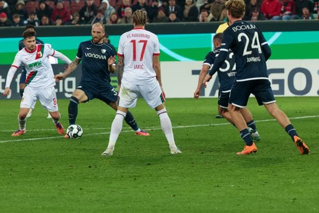 Aktion zwischen Elvis Rexhbecaj 8 (FC Augsburg), links, und Philipp Hofmann 33 (VfL Bochum), mit Kristijan Jakic 17 (FC Augsburg) und Mats Pannewig 24 (VfL Bochum), die zuschauen, FC Augsburg vs. VfL Bochum 1848, Fussball, Maenner, DFL, DFB-Pokal, Saison 2025 2026, WWK Arena, Zweite Runde, 28.10.2025 Augsburg Bayern Deutschland