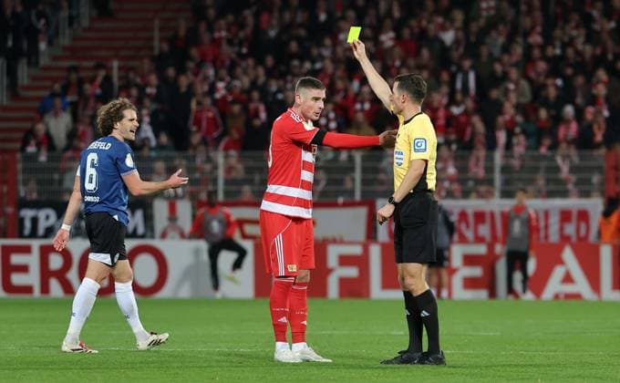 Schiedsrichter Harm Osmers zeigt gelbe Karte für Andrej Ilic Fußball Fussball DFB Pokal 2.Runde Herren Saison 2025 2026 29.10.2025 1.FC Union Berlin FCU vs. DSC Arminia Bielefeld DFL regulations prohibit any use of photographs as image sequences and or quasi-video.