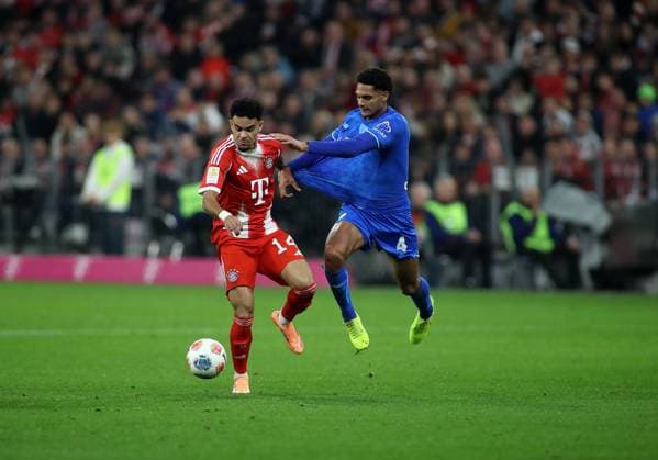 Fussball, Herren, Bundesliga, Saison 2025 2026, FC Bayern München - Bayer 04 Leverkusen, Allianz Arena Luis Diaz (FC Bayern München) (li.) mit Jarell Quansah (Bayer 04 Leverkusen) (re.) im Zweikampf um den Ball, Trikot ziehen DFB, DFL regulations prohibit any use of photographs as image sequences and or quasi-video