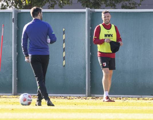 Jeffrey Gouweleeuw (FC Augsburg 6) ist nach Verletzung wieder auf dem Trainingsplatz, gut gelaunt mit Mütze und mit Sven Palinkasch (Co.-Trainer FC Augsburg); FC Augsburg, Training,
