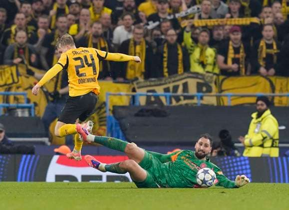 Manchester, England, 5th November 2025. Gianluigi Donnarumma of Manchester City (r) slides in to tackle Daniel Svensson of Borussia Dortmund (l) during the Manchester City vs Borussia Dortmund UEFA Champions League match at the Etihad Stadium, Manchester. Picture credit should read: Andrew Yates Sportimage EDITORIAL USE ONLY. No use with unauthorised audio, video, data, fixture lists, club league logos or live services. Online in-match use limited to 120 images, no video emulation. No use in betting, games or single club league player publications. SPI_042_AY_Man_City_Dortmund SPI-4268-0099