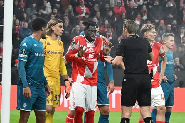06.11.2025, xsltx, Fussball UEFA Conference League, FSV Mainz 05 - AC Florenz v.l. Tommaso Martinelli (AC Florenz) Danny da Costa (FSV Mainz 05) Schiedsrichter Referee Lawrence Visser (Belgien) (DFL DFB REGULATIONS PROHIBIT ANY USE OF PHOTOGRAPHS as IMAGE SEQUENCES and or QUASI-VIDEO) Mainz