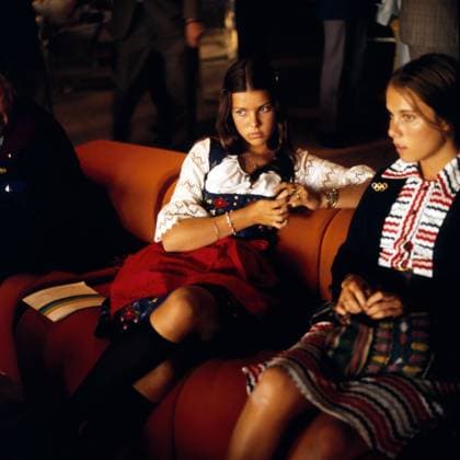 Olympische Sommer-Spiele München 1972 - Rahmenprogramm Prinzessin Caroline von Monaco (links) sitzt am Vorabend der Eröffnungsfeier der Olympischen Sommerspiele 1972 in München mit einer Freundin auf einem Sofa, gekleidet in ein traditionelles Dirndl. München Bayern Deutschland *** Olympic Summer Games Munich 1972 Framework Programme Princess Caroline from Monaco left sits at Eve the Opening ceremony the Olympic Summer Games 1972 in Munich with a Girlfriend on a Sofa, dressed in a Traditional Dirndl Munich Bavaria Germany Copyright: xUnitedxArchivesx xSvenxSimonxSportx SVS_95010000069