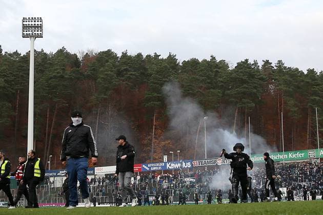 15.11.2025, xrekx, Fussball Regionalliga Suedwest, FC Homburg - SV Sandhausen v.l. Platzsturm SV Sandhausen Fans, Polizei mit Pfefferspray, Homburg Fans verbrennen die geklaute Fahne Banner von Sandhausen (DFL DFB REGULATIONS PROHIBIT ANY USE OF PHOTOGRAPHS as IMAGE SEQUENCES and or QUASI-VIDEO) Homburg