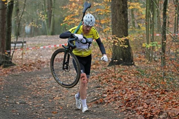 Stevens Cyclo-Cross-Cup. Elite-Feld, Masters und Junioren auf der Strecke Am Butterberg in Elmshorn. Der Gesamtführende Frederik von Hartwig (TS Klinkrade) muss sein Fahrrad nach einem Schaden auf der letzten Runde ins Ziel tragen.