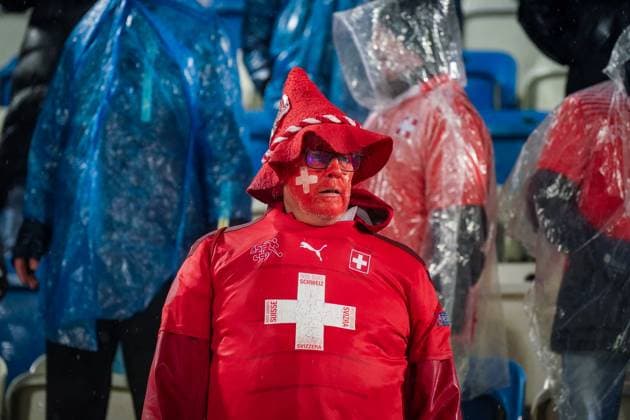 Fussball WM-Qualifikation 2025 26, 10. Spieltag Kosovo vs Schweiz Fadil-Vokrri-Stadion (Pristina): Pristina, Kosovo, Europa: Schweizer Fans im Starkregen, rot gekleidet, Supporter mit bemaltem Gesicht, Schals Schweiz Suisse SvizzerA Svizra, Ponchos, Fanblock, Emotionen, Auswärtssupport, Stimmung, Nässe, Wetterlage, Qualifikation, Fußballkultur, Medienrelevanz: Fanverhalten, Wetter, Sicherheit, Matchday. Pristina Kosovo Copyright: xJOERANxSTEINSIEKx