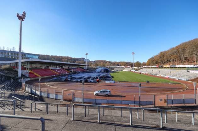 Das Leimbachstadion, Heimstaette (Heimstätte) der Sportfreunde Siegen. Vor der Haupttribuene (Haupttribüne) wird mit Waerme (Wärme), Warmer Luft unter eine Folie der Rasen aufgetaut. Es wird alles versucht, damit das Heimspiel am morgigen Samstag gegen den SC Fortuna Koeln (Köln) stattfinden kann. Fussball Regionalliga West, Leimbachstadion, Sportfreunde Siegen am 21.11.2025 in Siegen Deutschland.