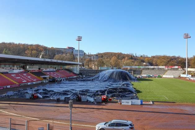 Das Leimbachstadion, Heimstaette (Heimstätte) der Sportfreunde Siegen. Vor der Haupttribuene (Haupttribüne) wird mit Waerme (Wärme), Warmer Luft unter eine Folie der Rasen aufgetaut. Es wird alles versucht, damit das Heimspiel am morgigen Samstag gegen den SC Fortuna Koeln (Köln) stattfinden kann. Fussball Regionalliga West, Leimbachstadion, Sportfreunde Siegen am 21.11.2025 in Siegen Deutschland.