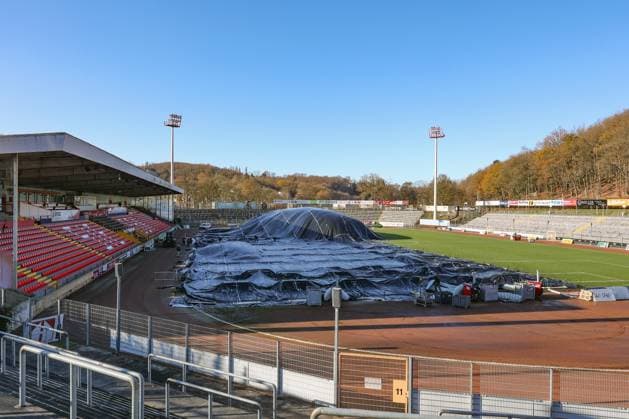 Das Leimbachstadion, Heimstaette (Heimstätte) der Sportfreunde Siegen. Vor der Haupttribuene (Haupttribüne) wird mit Waerme (Wärme), Warmer Luft unter eine Folie der Rasen aufgetaut. Es wird alles versucht, damit das Heimspiel am morgigen Samstag gegen den SC Fortuna Koeln (Köln) stattfinden kann. Fussball Regionalliga West, Leimbachstadion, Sportfreunde Siegen am 21.11.2025 in Siegen Deutschland.