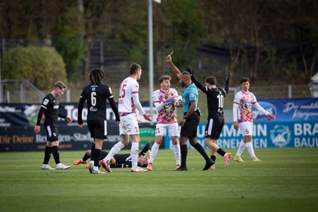 3. Liga: FC Viktoria Köln - SC Verl, 22.11.2025 Jonah Besong (Duisburg) zeigt Christoph Greger (Viktoria Köln, 15) die gelbe Karte ; Köln, 22.11.2025 - 15. Spieltag der 3. Fußball-Liga: FC Viktoria Köln - SC Verl im Sportpark Höhenberg in Köln. Die DFL-Bestimmungen verbieten die Verwendung von Fotografien als Bildsequenzen und oder Quasi-Videos. Copyright: xBEAUTIFULxSPORTS AxelxKohringx