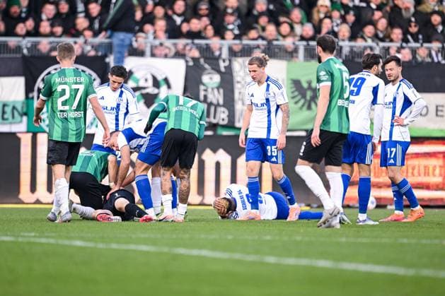 22.11.2025, Fussball, 2. Bundesliga, Saison 2025 2026, 13. Spieltag, Preußen Münster - FC Schalke 04, Johannes Schenk (Preußen Münster) liegt am Boden und Nikola Katic (FC Schalke 04) bringt ihn in die stabile Seitenlage, xRHR-FOTO YYx Copyright: KROEGER RHR-FOTOx RHR-FOTO YY