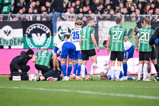 22.11.2025, Fussball, 2. Bundesliga, Saison 2025 2026, 13. Spieltag, Preußen Münster - FC Schalke 04, Johannes Schenk (Preußen Münster) liegt am Boden und Nikola Katic (FC Schalke 04) bringt ihn in die stabile Seitenlage, xRHR-FOTO YYx Copyright: KROEGER RHR-FOTOx RHR-FOTO YY