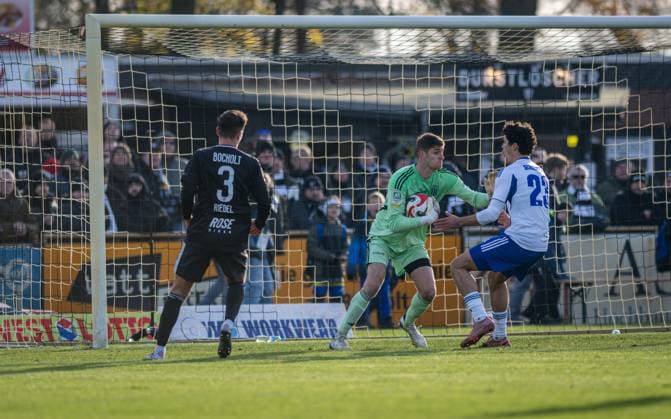 Fussball, Saison 2025 2026, Regionalliga West, 22.11.2025, 16. Spieltag, Herren, 1.FC Bocholt (schwarz) vs. FC Schalke 04 U23 (weiss) v.l.: Julian Riedel (1.FC Bocholt), Lucas Fox (Torwart 1.FC Bocholt), Jakob Sachse (FC Schalke 04 U23), Bocholt Stadion am Huenting Nordrhein-Westfalen Deutschland