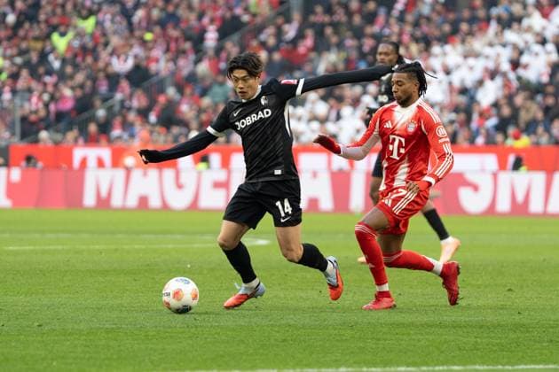 Yuito Suzuki (14 Freiburg) und Michael Olise (17 Bayern) in Aktion beim Bundesligaspiel FC Bayern München - SC Freiburg am 22.11.2025.