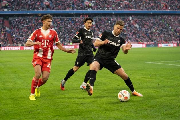 Tom Bischof (20 Bayern) und Lukas Höler (9 Freiburg) in Aktion beim Bundesligaspiel FC Bayern München - SC Freiburg am 22.11.2025.