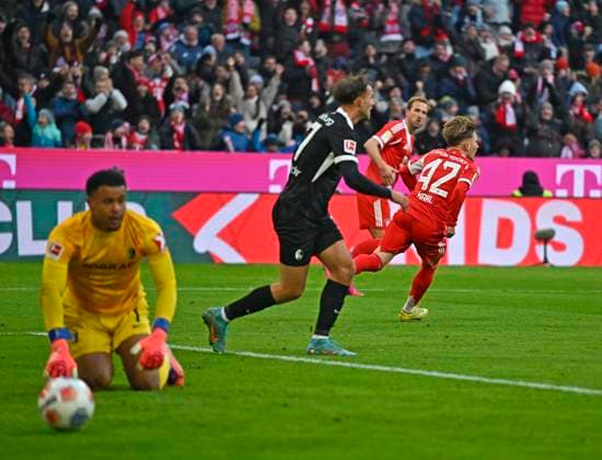 22.11.2025, Fussball Bundesliga 2025 2026, 11.Spieltag, FC Bayern München - SC Freiburg, in der Allianz-Arena München, Lennart Karl (FC Bayern München) trifft zum 1:2 gegen Torwart Noah Atubolu (SC Freiburg)