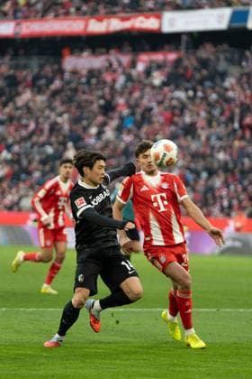 Yuito Suzuki (14 Freiburg) und Tom Bischof (20 Bayern) in Aktion beim Bundesligaspiel FC Bayern München - SC Freiburg am 22.11.2025.