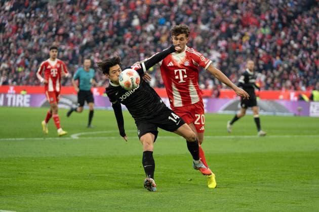 Yuito Suzuki (14 Freiburg) und Tom Bischof (20 Bayern) in Aktion beim Bundesligaspiel FC Bayern München - SC Freiburg am 22.11.2025.