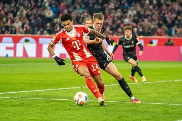 Luis Diaz (14 Bayern) und Matthias Ginter (28 Freiburg) in Aktion beim Bundesligaspiel FC Bayern München - SC Freiburg am 22.11.2025.