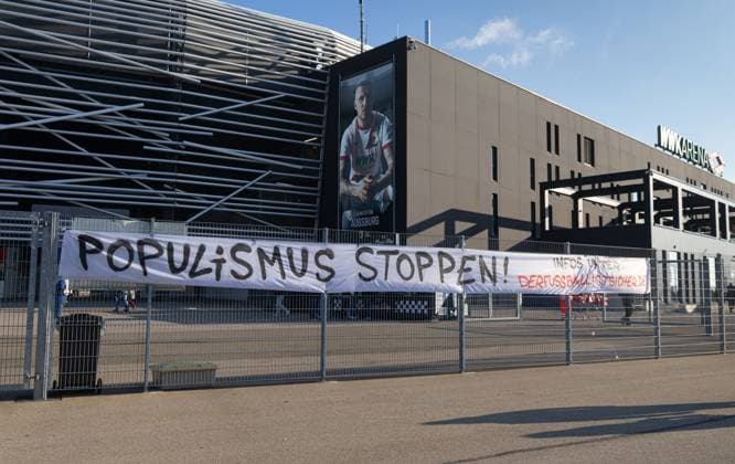 Protest-Plakat am Zaun vor der WWK-Arena: Populismus stoppen! FC Augsburg vs. Hamburger SV, 11. Spieltag; DFL REGULATIONS PROHIBIT ANY USE OF PHOTOGRAPHS AS IMAGE SEQUENCES AND OR QUASI-VIDEO.