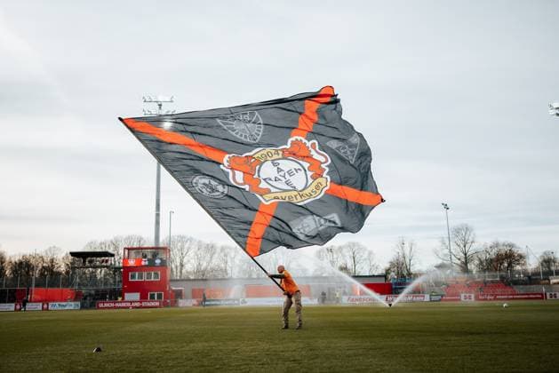 22.11.25, Frauen, Fussball, Google Pixel Frauen Bundesliga, Saison 2025 2026, Bayer 04 Leverkusen - SGS Essen, 11. Spieltag Ein Leverkusen Fan Volunteer schwenkt eine große Fahne auf dem Spielfeld, Totale Leverkusen Ulrich-Haberland-Stadion NRW Deutschland