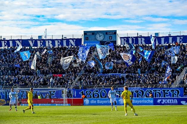 Fans des TSV 1860 Muenchen schwenken Fahnen und machen Stimmung, Fans, Publikum, Zuschauer, Stimmung, Atmosphaere, Stadion, 23.11.2025, München (Deutschland), Fussball, 3. Liga, TSV 1860 München - 1. FC Saarbrücken, DFB DFL REGULATIONS PROHIBIT ANY USE OF PHOTOGRAPHS AS IMAGE SEQUENCES AND OR QUASI-VIDEO.