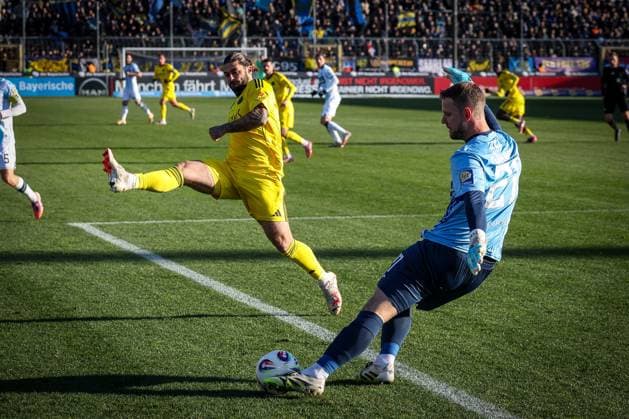 Thomas Daehne 21 (TSV 1860 Muenchen) mit einem Abschlag, den Dominic Baumann 30 (1. FC Saarbruecken) blockt, TSV 1860 Muenchen vs. 1. FC Saarbruecken, Fussball, Dritte Liga, DFL, Saison 2025 2026, Hinrunde, 15. Spieltag, 23.11.2025 DFB regulations prohibit any use of photographs as image sequences and or quasi-video Muenchen Bayern Deutschland